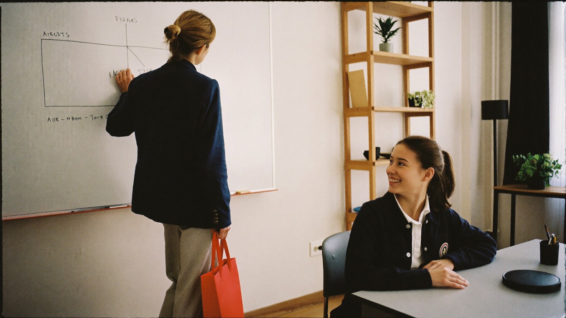 A tutor explaining a diagram at a whiteboard to a smiling student